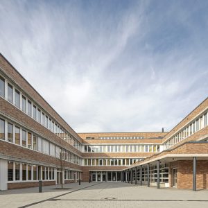 Langes Ziegelgebäude mit zahlreichen Fenstern und einem Innenhof