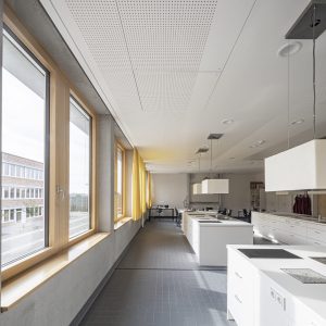 Lichtdurchfluteter, weitläufiger Raum mit Holzfenstern und modernen Kochfeldern mit Spülbecken.